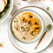 dairy free mushroom soup in bowl topped with sliced mushrooms and sprigs of thyme