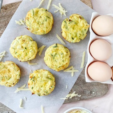 6 egg and leek muffins on white baking paper next to some eggs in dish
