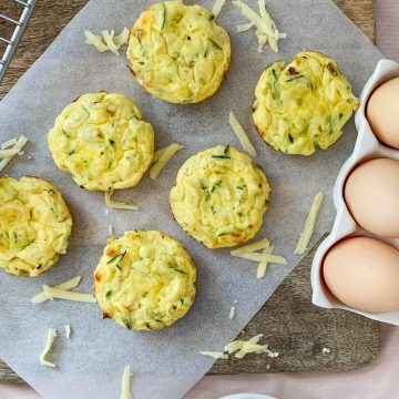 6 gluten free savoury muffins on wooden board next to a tray of eggs