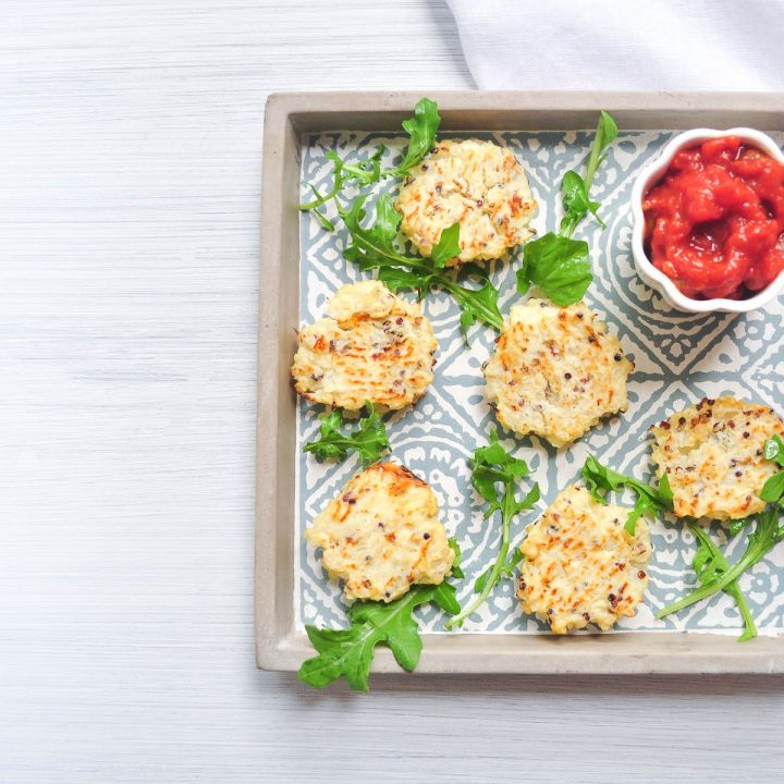 tray of cauliflower cheese bites sprinkled with rocket and served with tomato dip