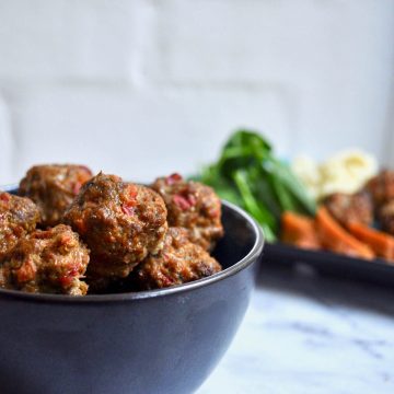black bowl of lamb meatballs with sweet potato and broccoli behind