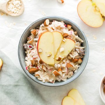 healthy bircher muesli in blue bowl topped with apple and almonds