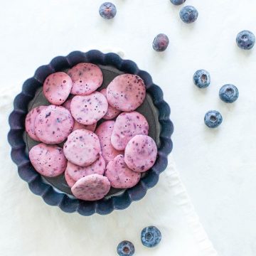 blueberry drops in small baking tin with blueberries dotted around it