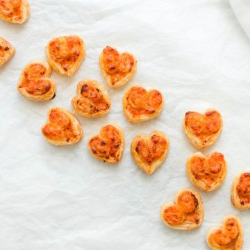 savoury puff pastry pinwheel hearts scattered across white background