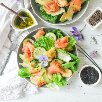 smoked salmon caesar salad on blue plates decorated with purple pansy and flowers