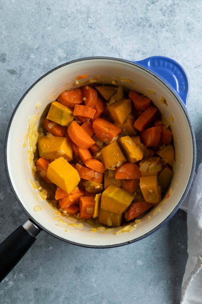 the cooked pieces of carrot and pumpkin in a pan with the spices added