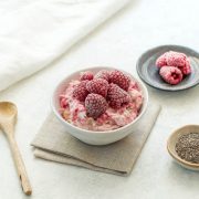 raspberry bircher overnight oats topped with frozen raspberries