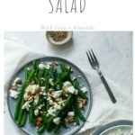 blue plate topped with green bean salad with feta and almonds on white napkin