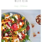 orange and carrot salad with feta on blue dish with rocket, dill and almonds