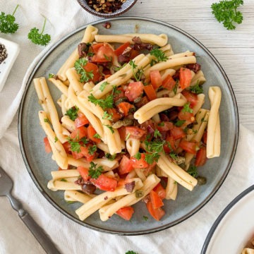 blue plate filled with cold puttanesca pasta salad