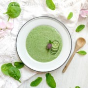 Bowl of green cucumber soup topped with slices of cucumber and chive flower