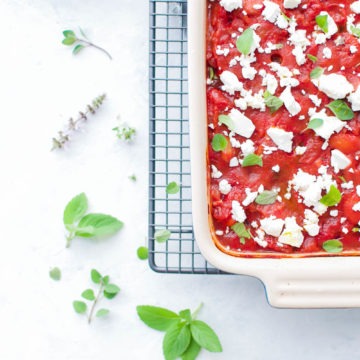 dish of gigantes plaki (Greek baked beans) on cooling rack sprinkled with herbs and feta cheese