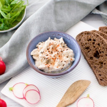 Hungarian cheese spread topped with caraway seeds in a bowl with rye bread and radishes