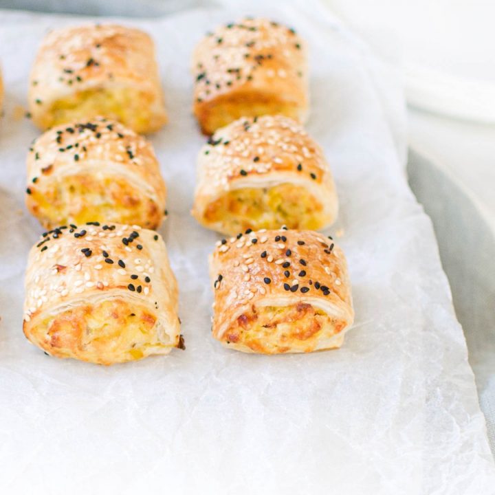 six leek and ricotta rolls on white background sprinkled with sesame seeds