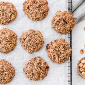 gluten free chocolate cookies with hazelnut flour on cooling rack with bowl of hazelnuts on the right side