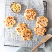 savoury cheese welsh cakes in flower shape on a tray sprinkled with grated cheese