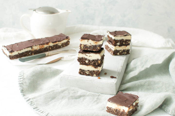 forty five degree angled shot of stacked Nanaimo bars with a unsliced rectangle behind