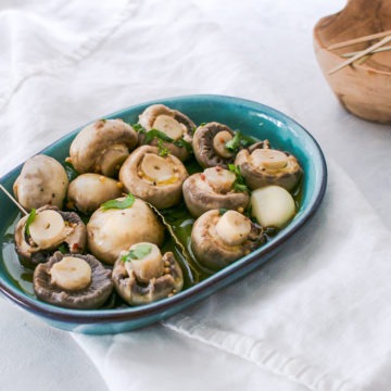 marinated mushrooms in blue dish sprinkled with fresh parsley