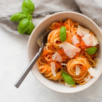 pasta al pomodoro in bowl with fresh basil and parmesan shavings