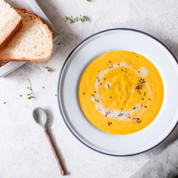 Bowl of creamy ginger & carrot soup with bread on the side
