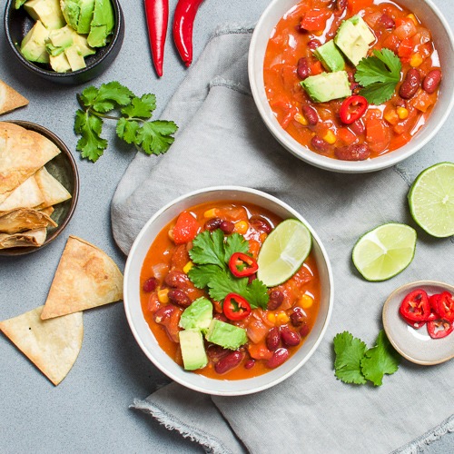 Two bowls of mexican bean soup with chillies & herbs