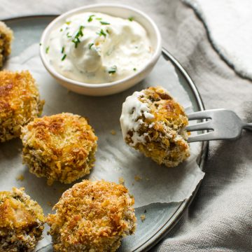 crispy baked garlic mushrooms with one on a fork just dipped in chive dip