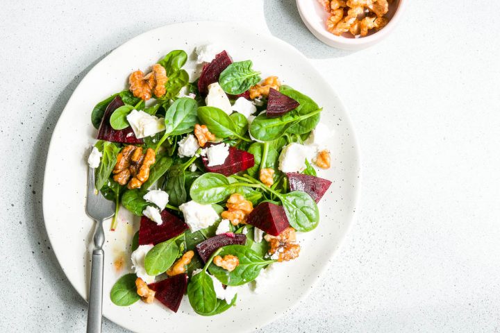 a single white plate of beetroot and feta salad with walnuts and spinach to show the beautiful colours of the salad