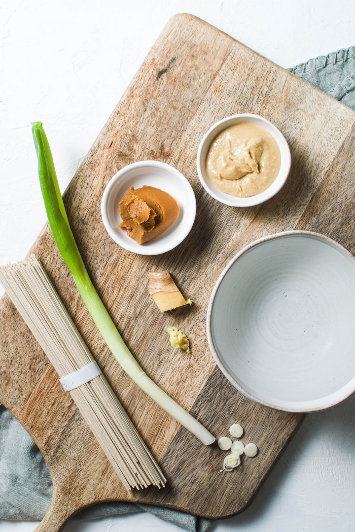 ingredients for soup: noodles, miso paste, peanut butter, ginger, spring onion and water