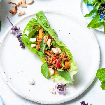 Thai lettuce cups overhead picture on a plate with bowl of nuts and other ingredients around
