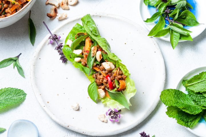 Thai lettuce cups overhead picture on a plate with bowl of nuts and other ingredients around