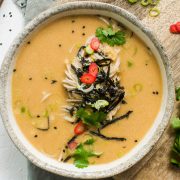overhead photo of a bowl of peanut miso soup with noodles topped with nori and sesame seeds