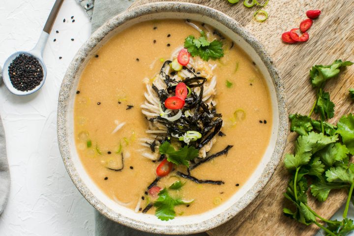 overhead photo of a bowl of peanut miso soup with noodles topped with nori and sesame seeds
