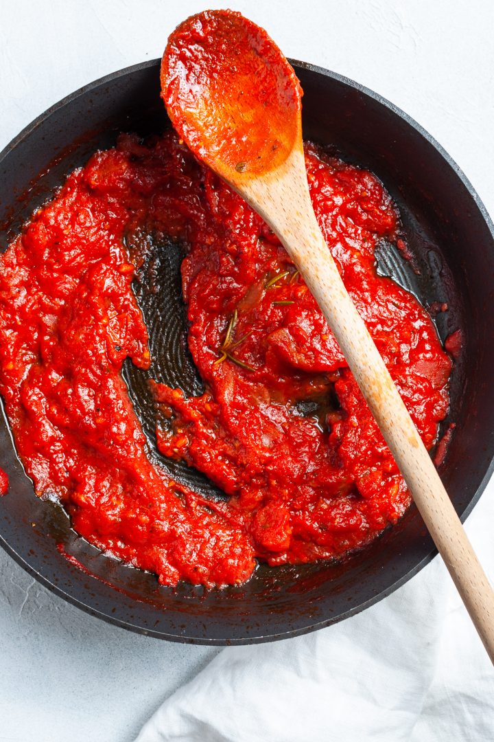 Pan of cooked homemade pizza sauce, a line made with the spoon showing its thick texture
