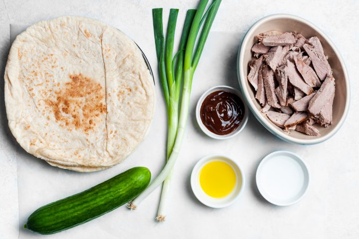 the 7 ingredients needed to make the lamb wraps shown in individual bowls, the spring onion/scallion and cucumber left whole