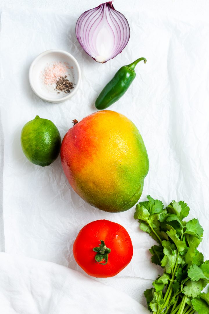 ingredients for mango pico de gallo: fresh mango, red onion, jalapeno, tomato, coriander (cilantro), lime and salt and pepper 