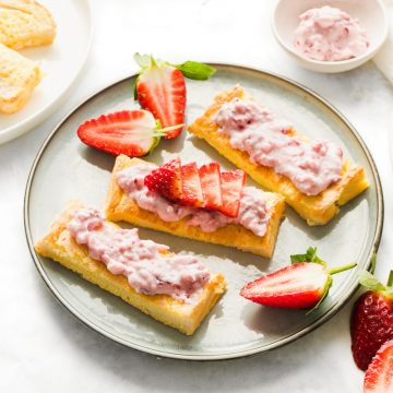angled shot of 3 sticks of french toast on plate topped with ricotta and sliced strawberries, other sticks of toast just visible