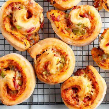 overhead close up of cooked pizza scrolls in a random pattern on wire cooking rack