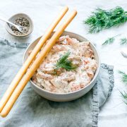 bowl of smoked salmon pate with two breadsticks on the side of the bowl, ready to dip into the salmon