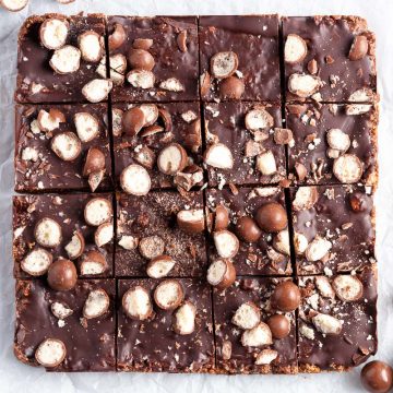 overhead photo of Maltesers traybake on white background, a few broken Maltesers scattered around the edges