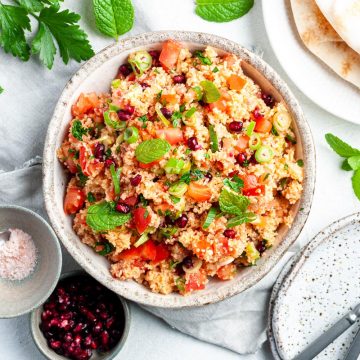 kisir in a bowl ready to eat, with flatbread, pomegranate seeds and salt to serve
