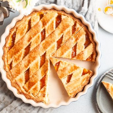 overhead photo of apricot jam tart with two pieces cut, a slice on a plate and the other still in the dish
