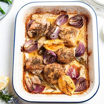 baked lemon chicken traybake in white enamel tray, green beans and black pepper to serve, just visible