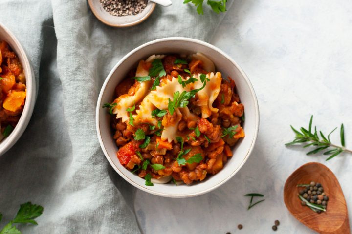 overhead photo of lentil ragu served in a bowl with bow tie pasta.