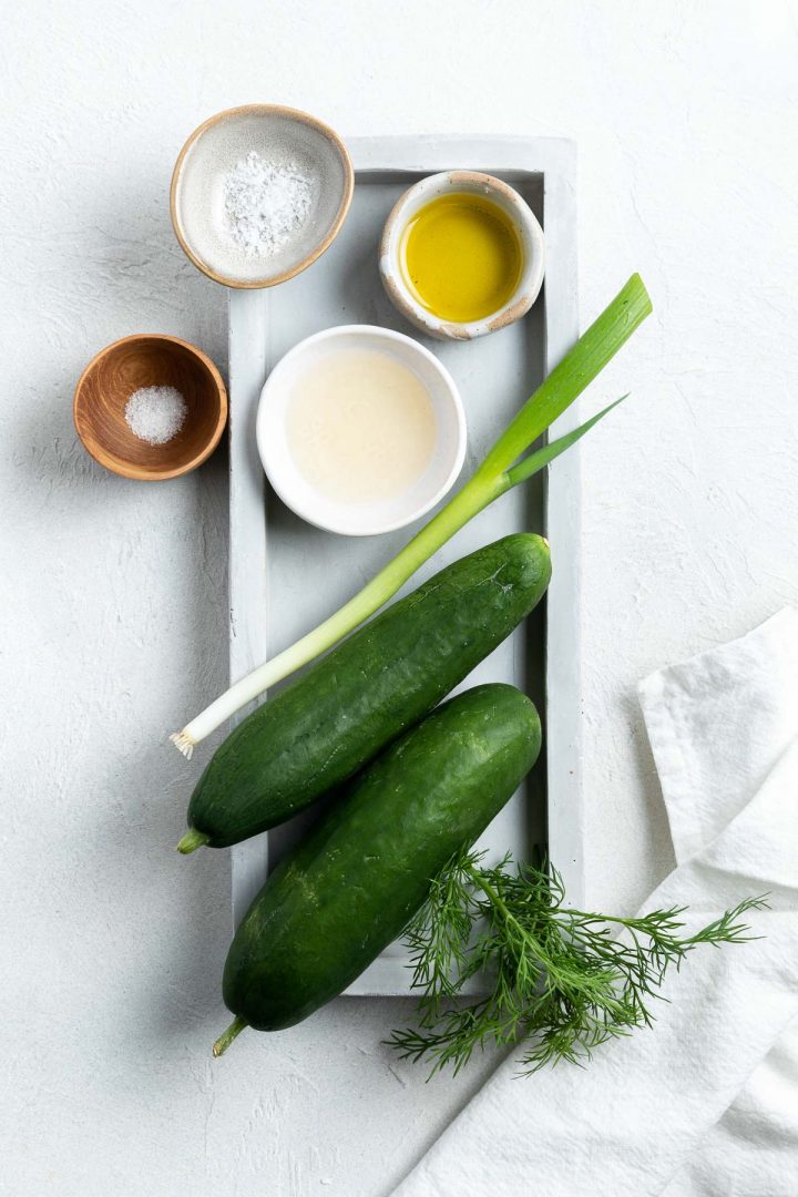 The ingredients needed to make the cucumber salad laid out on a grey tray.