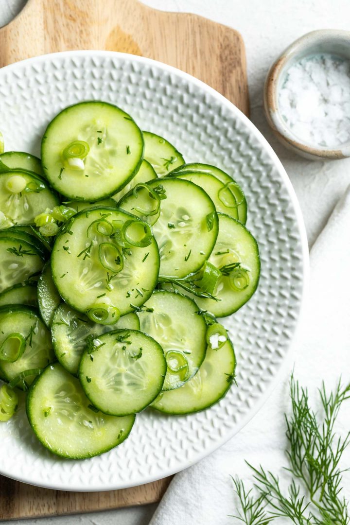 close up of gurkensalat on a white plate, sprinkled with fresh dill, ready to serve