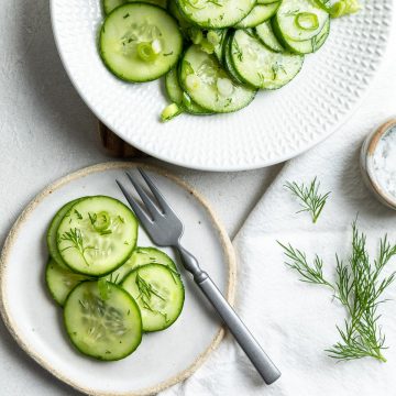 close up of cucumber salad on a small plate with a fork ready to eat