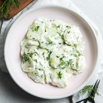 overhead photo of Mizeria in a pale pink bowl, sprinkled with chopped fresh dill