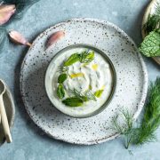 overhead photo of Haydari in a bowl, surrounded by fresh mint and dill