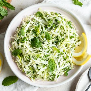 Lebanese malfouf salad in white bowl served with lemon wedges and topped with fresh mint