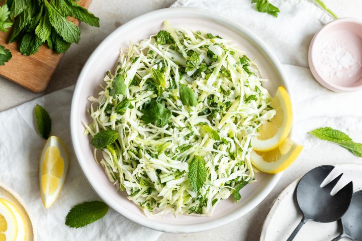 Lebanese malfouf salad in white bowl served with lemon wedges and topped with fresh mint